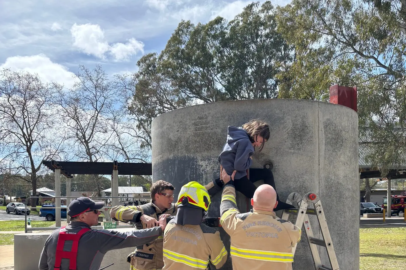 STUCK: Firefighters help young Harriet Lipshut out of a pipe she had been trapped in for 20 minutes at Apex Park.