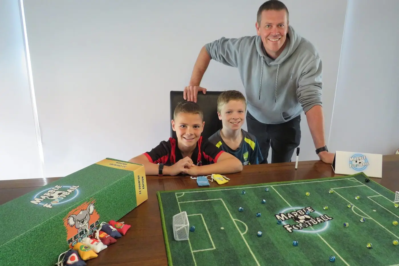 FUN AND GAMES: Craig Kerlin with chief game testers Jimmy Kerlin (8) and Ryan Allan (11) and the Marble Football prototype.  PHOTO: Simone Kerwin\\n