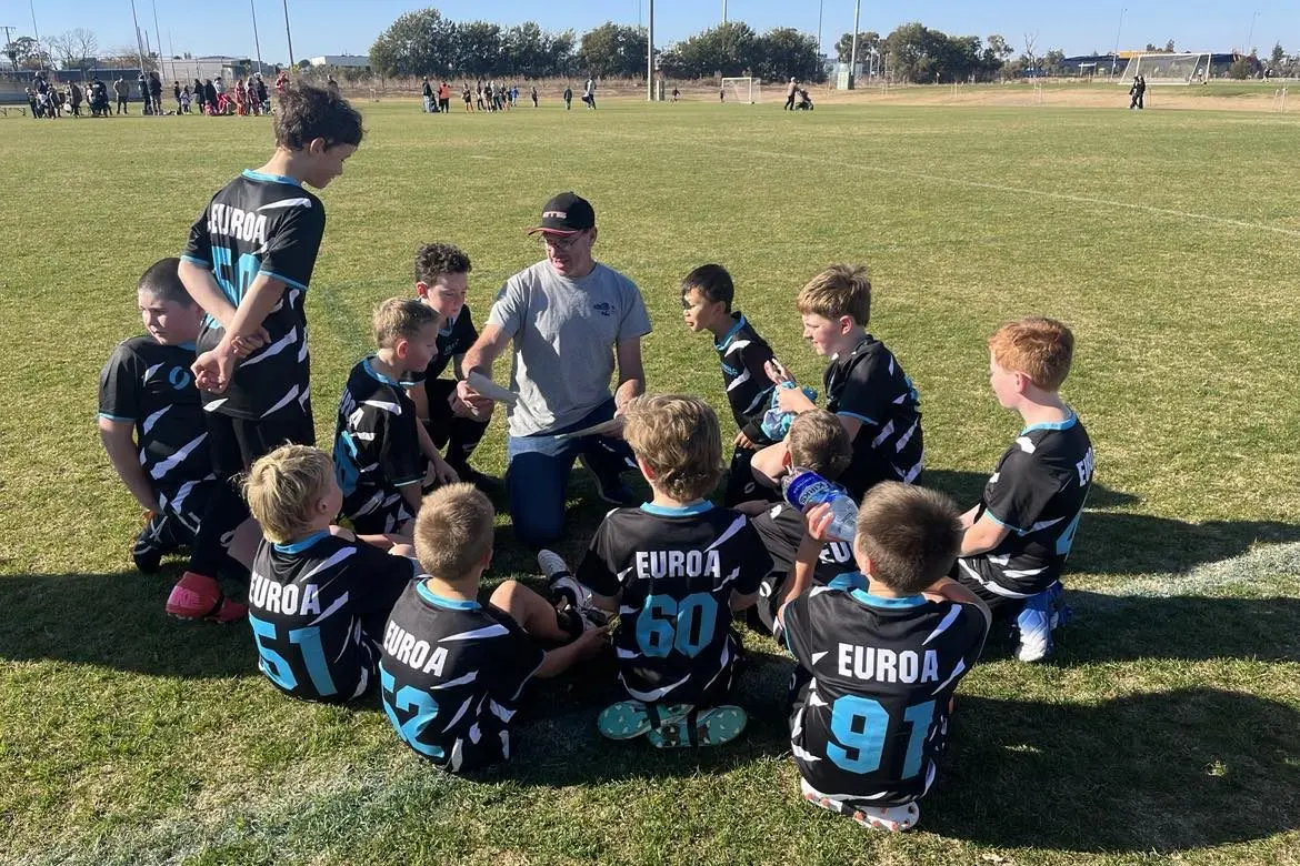 COACHES HUDDLE: Coach David gathers the team to celebrate their 5\\u20133 win.