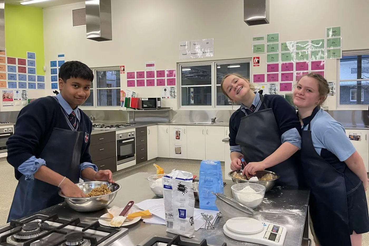KIDS IN THE KITCHEN: Cathedral College students Nelitha Abeykoon, Lizzy Healy and Darcy Murray prepare homemade goodies for the Wangaratta Night Shelter.\\n